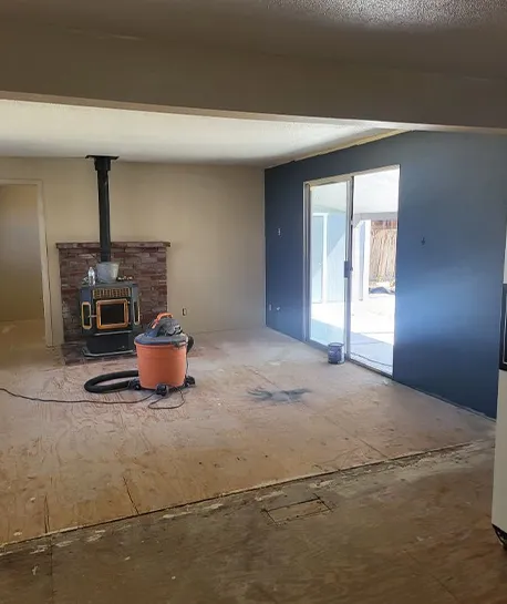 A partially renovated living room with exposed flooring and a fireplace, demonstrating the benefits of residential remodeling.