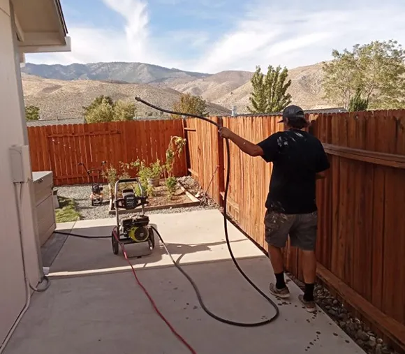 A professional using a pressure washer on a wooden deck in Carson City, NV, showcasing expert cleaning services.